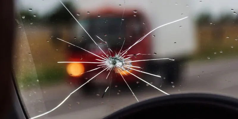 Beschädigte Windschutzscheibe mit Riss durch Steinschlag, aufgenommen aus dem Auto.