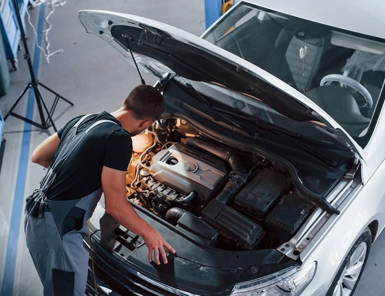 KFZ-Mechaniker überprüft den Motorraum eines Fahrzeugs in der Autowerkstatt.