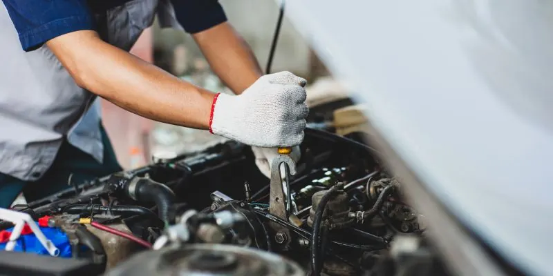Kfz-Mechaniker führt Wartungsarbeiten am Motor durch - professionelle Autoreparatur in der Werkstatt.