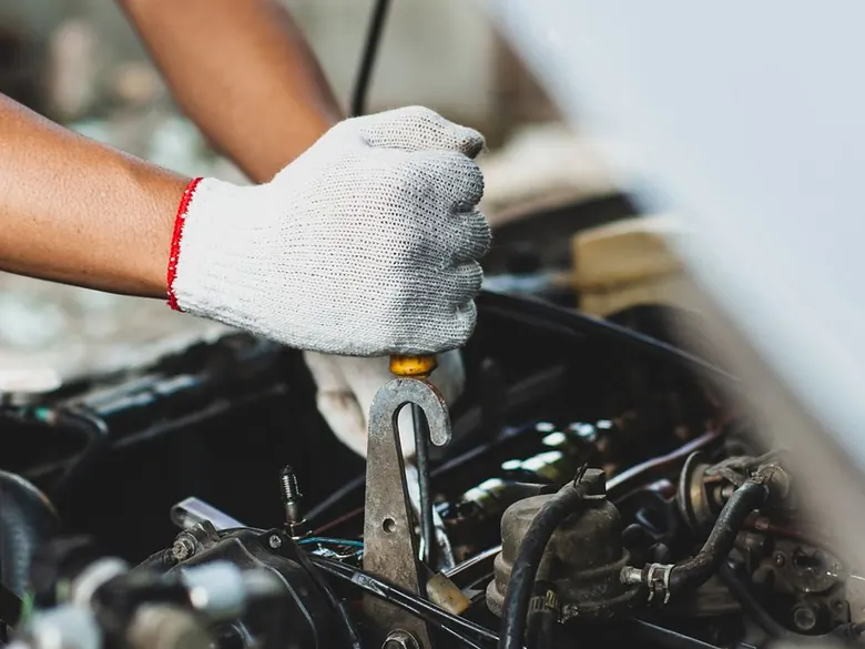 Nahaufnahme eines Mechanikers, der mit einer Ratsche an einem Fahrzeugmotor arbeitet.