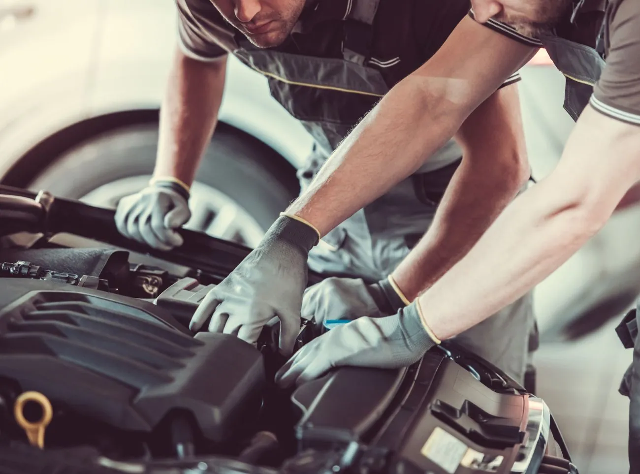 Zwei KFZ-Mechaniker überprüfen den Motor eines Fahrzeugs in der Werkstatt.